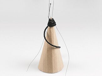 Cardboard cone with beaded wire spiraling around the top, showing how to insert two vertical wires